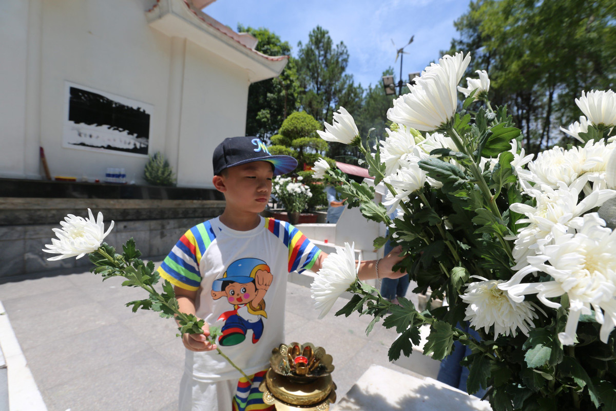 Một học sinh dâng hoa tại phần mộ 10 nữ liệt sỹ thanh niên xung phong.