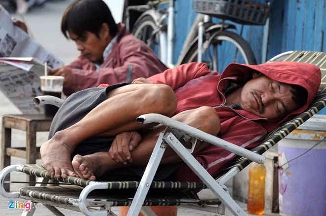 Người đàn ông làm nghề bơm vá xe trên vỉa hè đường Lý Thái Tổ (quận 5) ngủ nướng dù trời đã sáng vì trời lạnh.