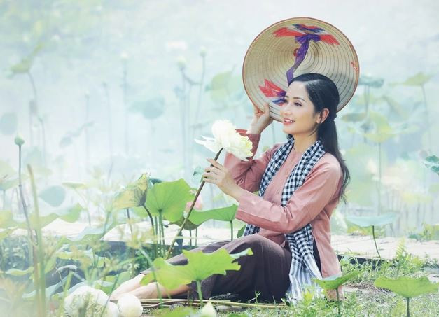 Trong bộ áo bà ba choàng thêm chiếc khăn rằn và nón lá che nghiêng, cô gái Hà Nội Vũ Diệu Thảo hóa thân thiếu nữ Nam Bộ duyên dáng, chịu thương chịu khó trên đầm sen đang nở rộ (Ảnh: Hòa Nguyễn).