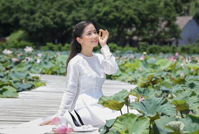 Với tà áo dài trắng tinh khôi, Vũ Diệu Thảo hóa thành cô nữ sinh trong sáng, hồn nhiên. Nụ cười tỏa nắng giữa sắc xanh của lá, sắc hồng của hoa gieo vào lòng người cảm xúc tươi mới, trong trẻo (Ảnh: Hòa Nguyễn).