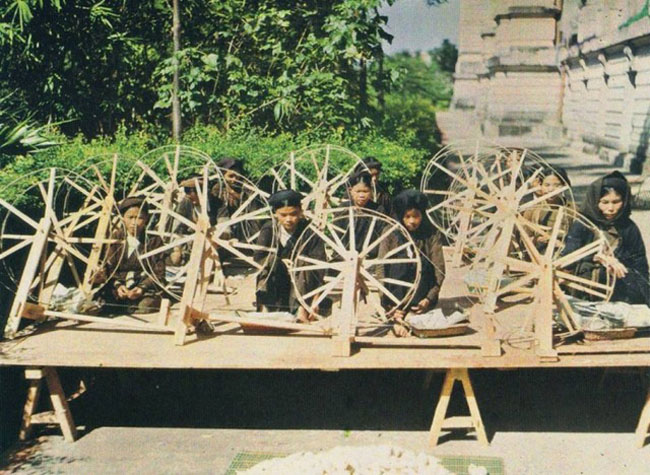 Phụ nữ ngồi quay sợi.