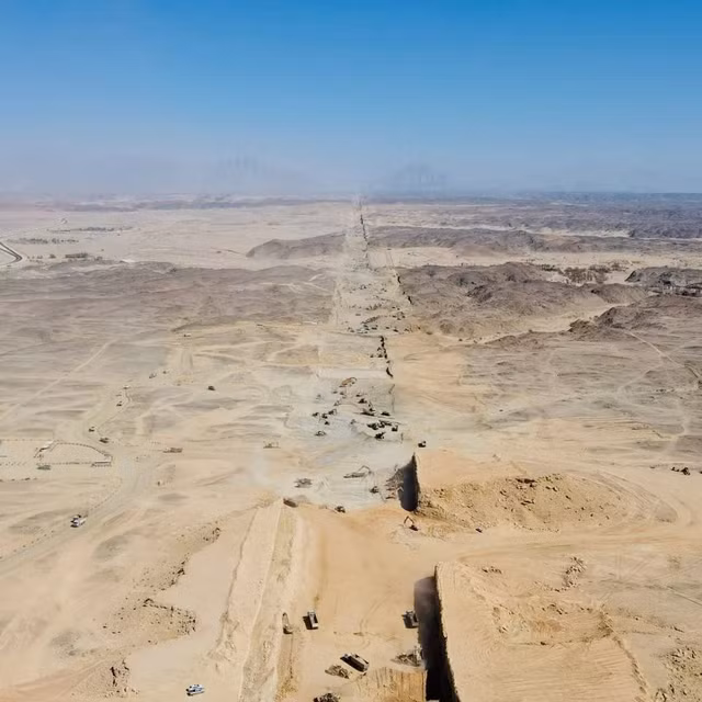 Trong video được ghi hình từ trên cao, nhiều máy xúc làm việc giữa sa mạc trống trải. Các cỗ máy đang tạo một rãnh rộng, nơi dự kiến đặt móng của thành phố thẳng.