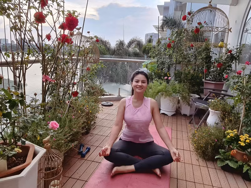 Nữ người mẫu ngồi thiền ở ban công ngập tràn hoa tươi.