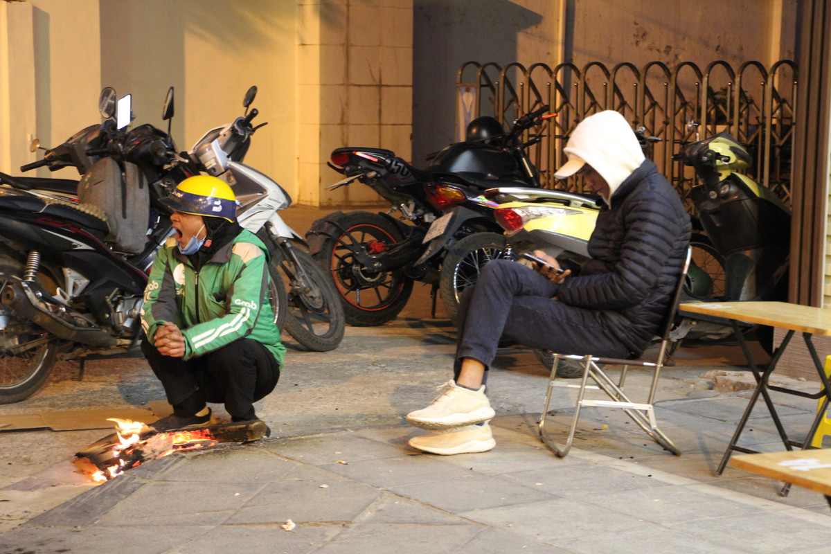 Anh Nguyễn Mạnh Côn, tài xế xe công nghệ tranh thủ sưởi ấm tại một điểm đốt lửa trên đường Lê Trọng Tấn. Anh Côn tỏ ra mệt mỏi và buồn ngủ vì đã chạy xe suốt một ngày trong thời tiết lạnh buốt.