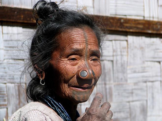 Tương truyền, phụ nữ bộ tộc Apatani (Ấn Độ) nổi tiếng với vẻ đẹp sắc nước hương trời. Phong tục đục hai lỗ ở cánh mũi rồi nhét đồng xu vào sau đó đã ra đời để giúp họ tránh bị các bộ lạc khác bắt cóc, đồng thời cũng để đánh dấu sự trưởng thành.