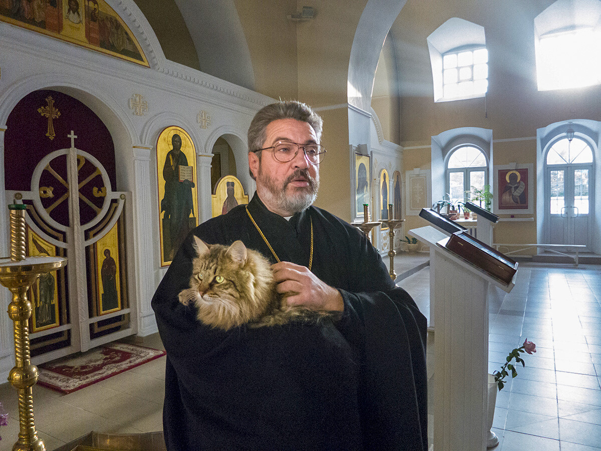 Linh mục người Nga Pyotr Dinnikov đang bế chú mèo cưng Vasik của mình tại nhà thờ Elijah the Prophet ở Lemeshevo. Ảnh: AP.