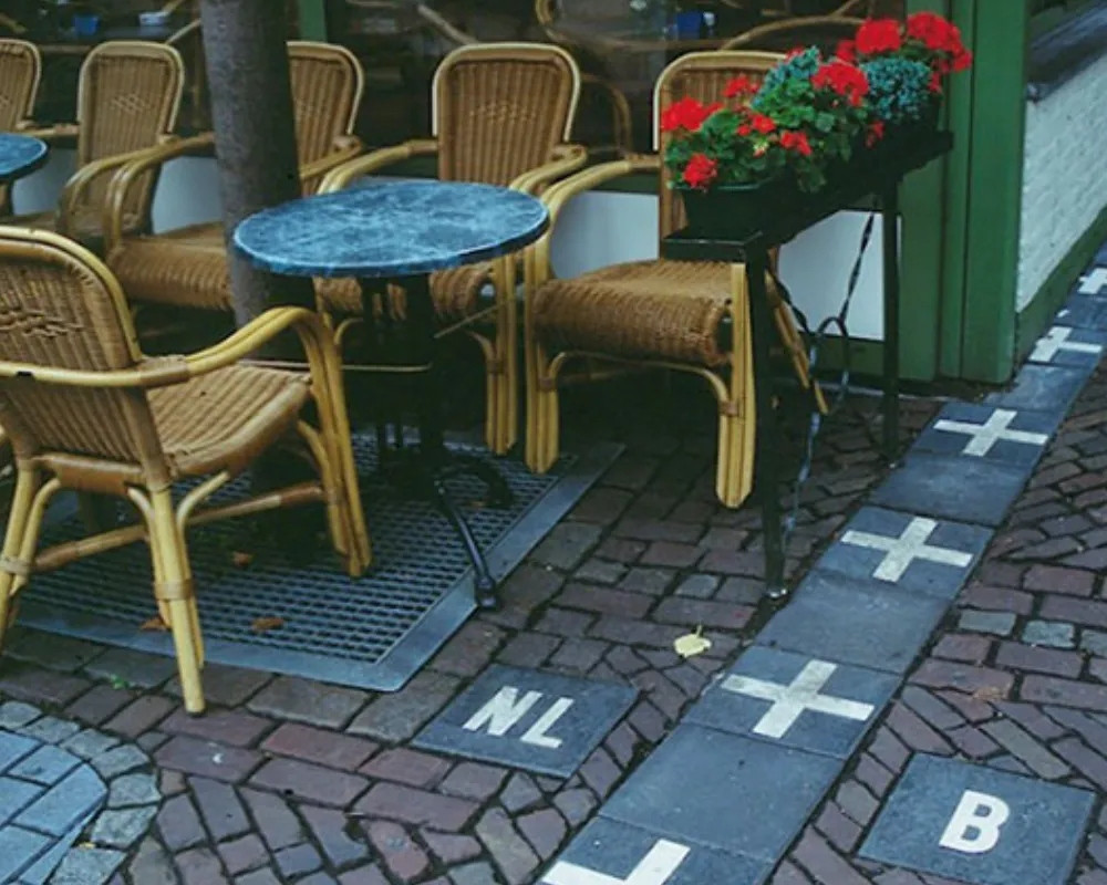 Du khách có thể bước vào quán cà phê tại Hà Lan và rời khỏi đó để đặt chân lên đất Bỉ bởi đường biên giới của hai nước chỉ cách nhau bởi những ô gạch. Ảnh: IT.