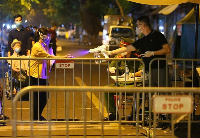 Xịt sát khuẩn tay với những người chuẩn bị rời khỏi khu vực phong tỏa. (Ảnh: Hoàng Hiếu/TTXVN)