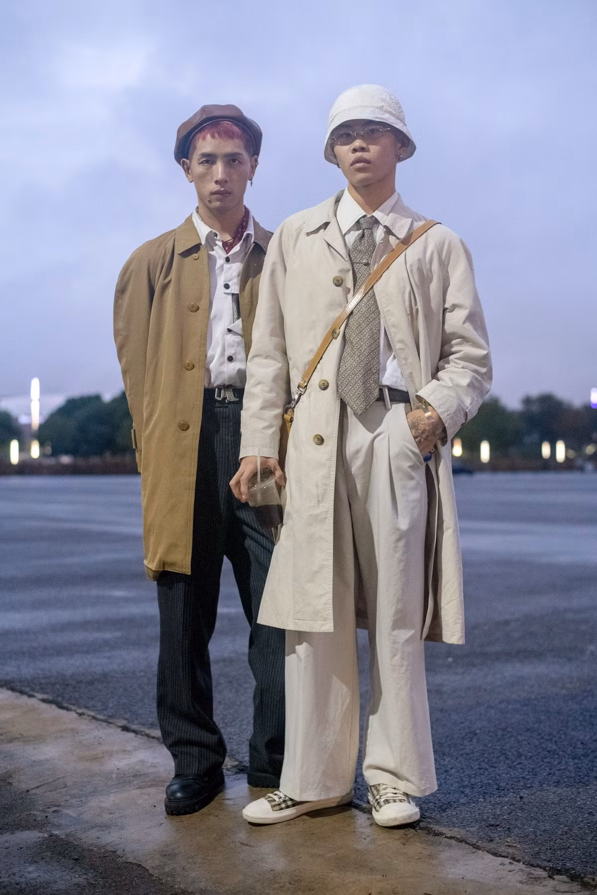 2 anh chàng này lại chọn combo kinh điển áo sơ mi trắng cũng quần âu và khoác ngoài là áo trench coat trơn màu. Tuy nhiên set đồ này lại trông mới lạ hẳn nhờ chiếc mũ bucket và mũ beret độc đáo.