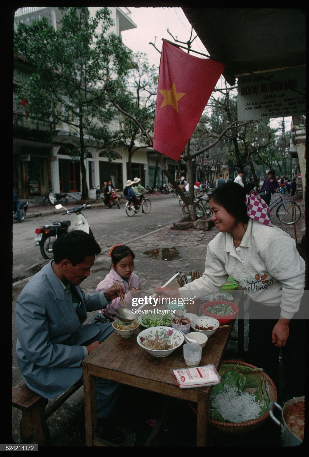 Trong ảnh, hai bố con đang đi ăn một quán bún vỉa hè tại Hà Nội ngày mùng 3 Tết năm 1994. Những ngày này, tìm được quán mở vào Tết không phải chuyện dễ dàng. Ảnh: Steven Raymer.