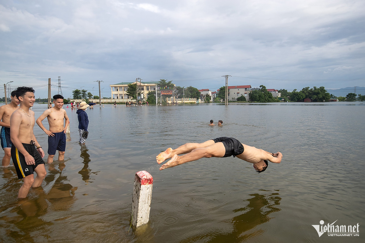 Những ngày này, thanh niên làng được dịp bơi lội ngay trên cánh đồng ngập nước. Ảnh: Phạm Quốc Dũng