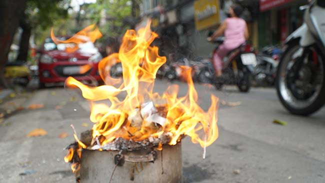 Một gia đình để nồi đốt vàng mã ngay dưới lòng đường.