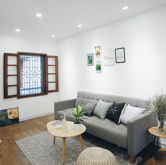 Phòng khách của ngôi nhà sáng đẹp như nhà mẫu sau khi được sơn trắng đồng bộ, làm lại trần, sàn gỗ, kết hợp với đồ nội thất xinh xắn.