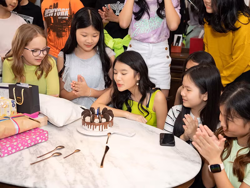 Cô nhóc thổi nến mừng sinh nhật bên những người bạn thân thiết.