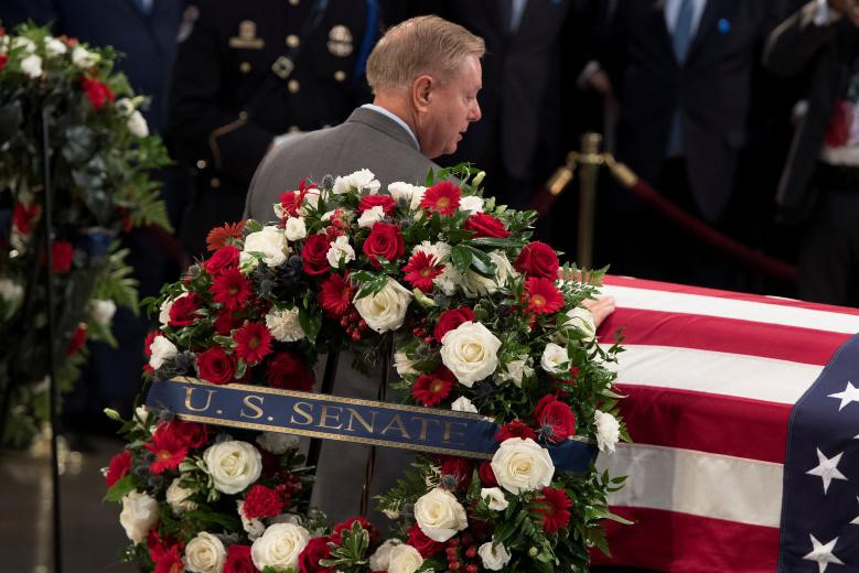 Sau khi các thành viên gia đình cầu nguyện bên linh cữu, bạn bè thân hữu và các nhân viên chính phủ Mỹ tới nói lời tiễn biệt. "Tùy vào từng vấn đề, John có thể là đồng minh trung thành nhất hoặc là người bất đồng cứng đầu nhất của chúng ta", Thượng nghị sĩ Cộng hòa Mitch McConnell nói về McCain, người nổi tiếng sẵn sàng phản bác lại các lãnh đạo đảng mình (Cộng hòa) vì lợi ích chung. Trong khi đó, lãnh đạo Hạ viện Paul Ryan gọi ông McCain là "một trong những tâm hồn dũng cảm nhất nước Mỹ từng sinh ra". Trong ảnh, thượng nghị sĩ Lindsey Graham, bạn thân của John McCain, nói lời từ biệt bên linh cữu.