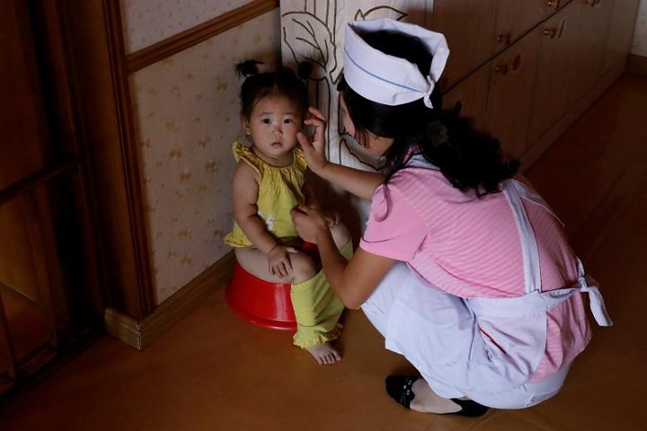 Cô bảo mẫu đang chăm sóc một bé gái tại một nhà trẻ dành cho con cái của công nhân nhà máy nói trên.