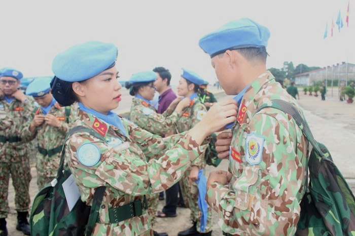 Thiếu úy Sa Minh Ngọc sửa lại quân trang cho một đồng đội nam.