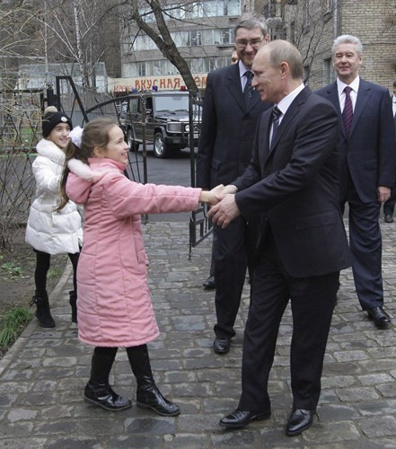 Ông Putin mỉm cười thân thiện, bắt tay một cô bé. Ảnh: Imgur