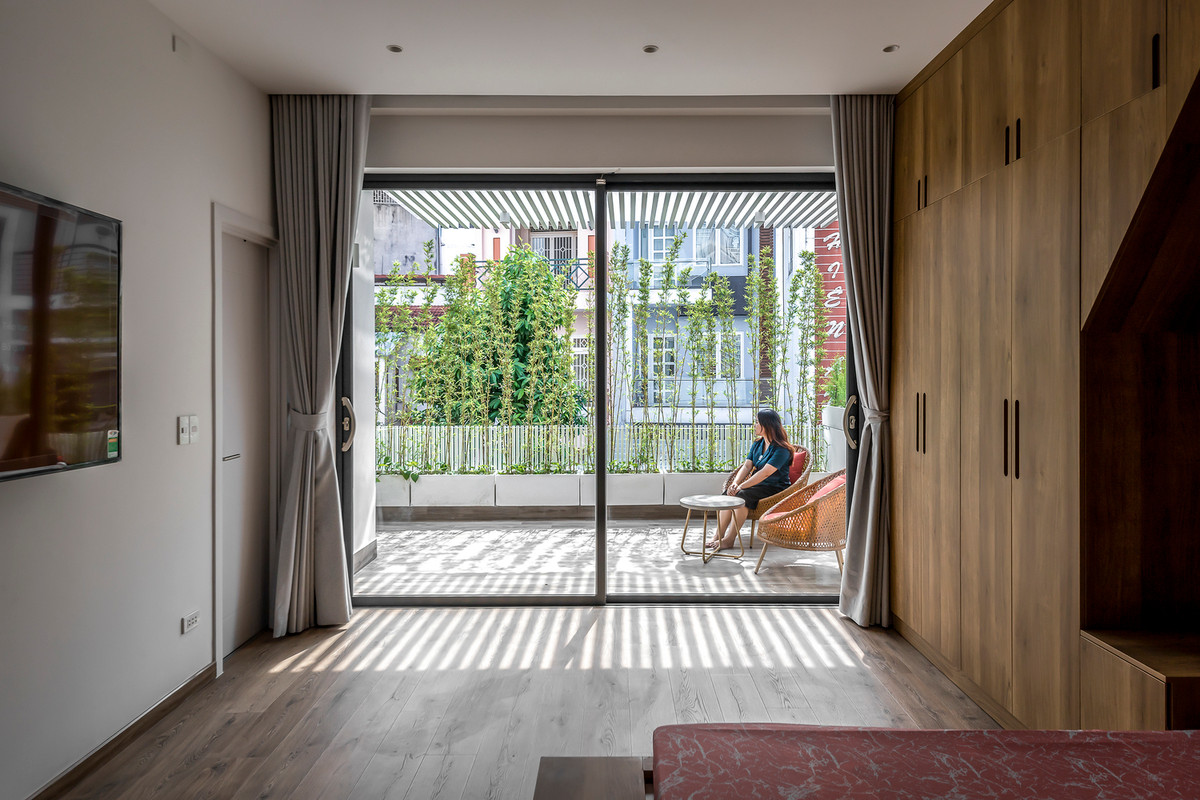 Phòng ngủ thiết kế vách kính lớn nhìn ra mảng cây xanh và lấy sáng tự nhiên từ các ô thông tầng tạo sự thông thoáng, giải phóng được tầm nhìn.