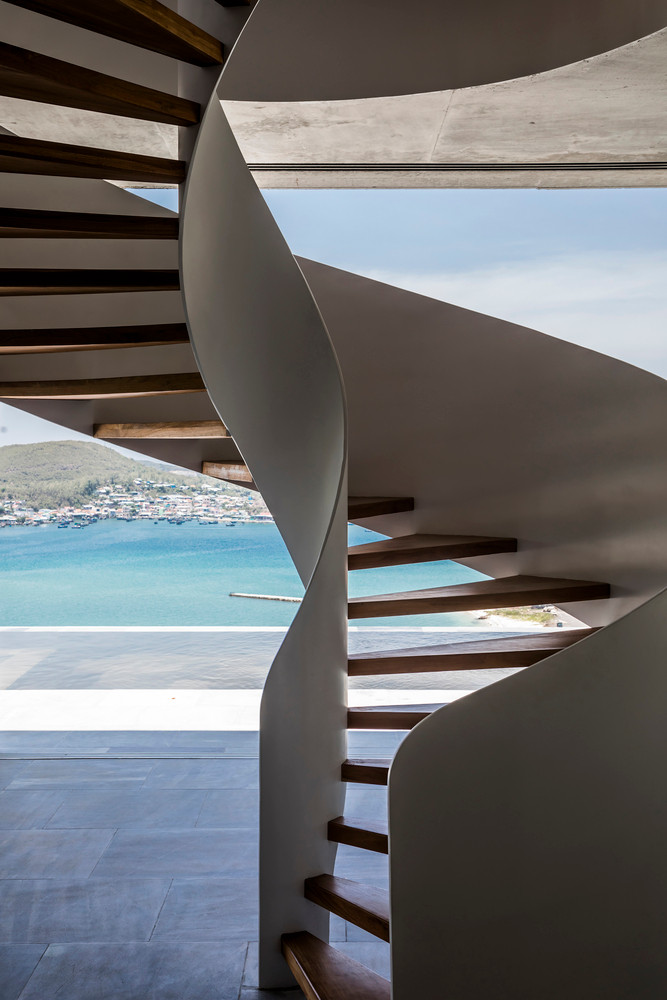 Cầu thang xoắn ngoài trời dẫn xuống tầng trệt. Một không gian khoáng đạt mở ra trước mắt. Kiến trúc sư loại bỏ hoàn toàn các cột trụ bê tông, toàn bộ phần trần được chống đỡ bởi các thanh trụ kim loại dẹt tích hợp với khung kính.