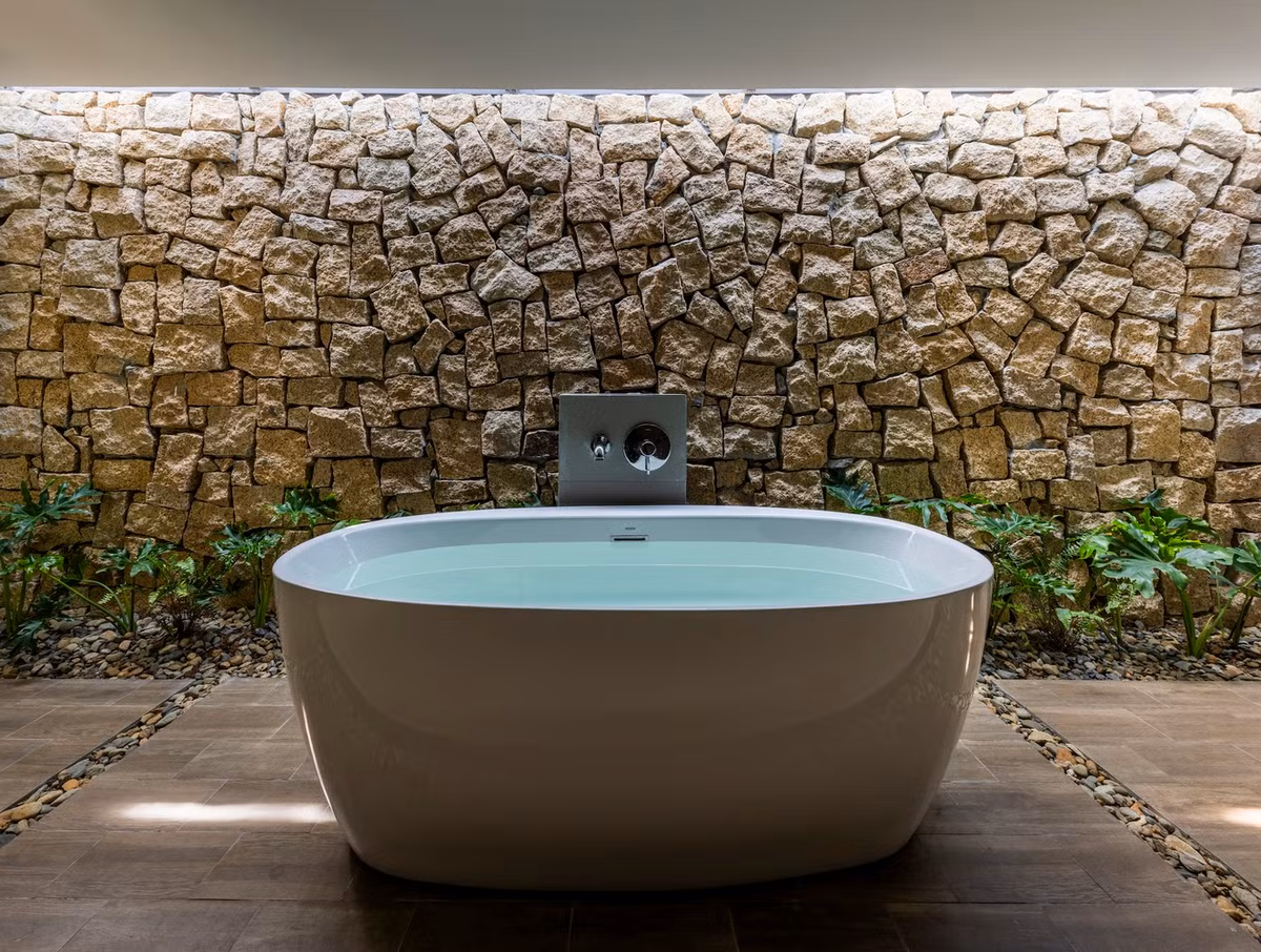 Để tăng cường sự kết nối với thiên nhiên, các yếu tố đá tự nhiên được kết hợp xuyên suốt, từ phòng tắm đến sân vườn.