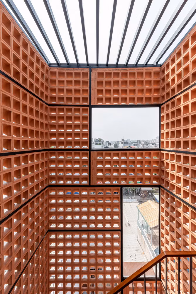 Mặt sau của cầu thang ốp gạch bông gió, loại ngói phổ biến ở địa phương, tạo sự thông thoáng đối lưu nhưng không bị mưa tạt, đồng thời kết hợp các tấm kính để lấy sáng tạo cửa sổ nhìn lên trời. Ảnh: Lonton Studio