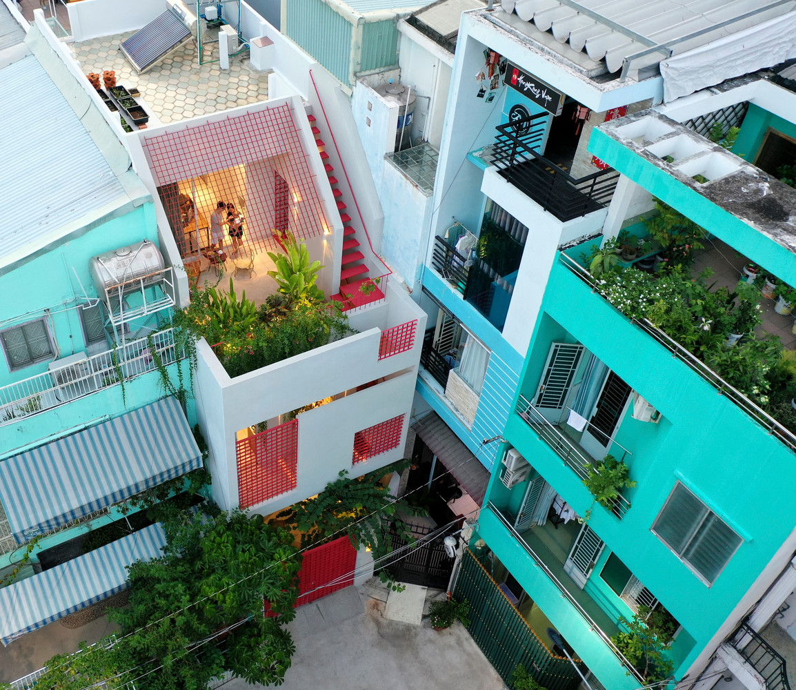 Để hạn chế sự ồn ào, náo nhiệt từ bên ngoài, mặt tiền của nhà phố được che chắn bởi những ô lưới sắt màu đỏ. Ảnh: Paul Phan