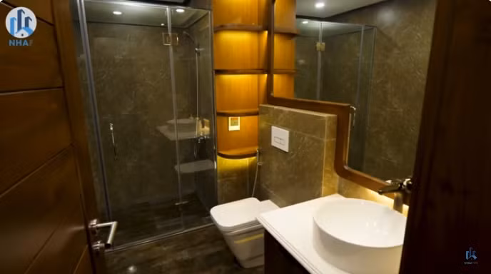 Phòng vệ sinh chung thiết kế đơn giản nhưng nội thất hiện đại. Đáng chú ý, gương treo trong phòng tắm cũng có viền gỗ óc chó xung quanh. Ảnh: chụp màn hình