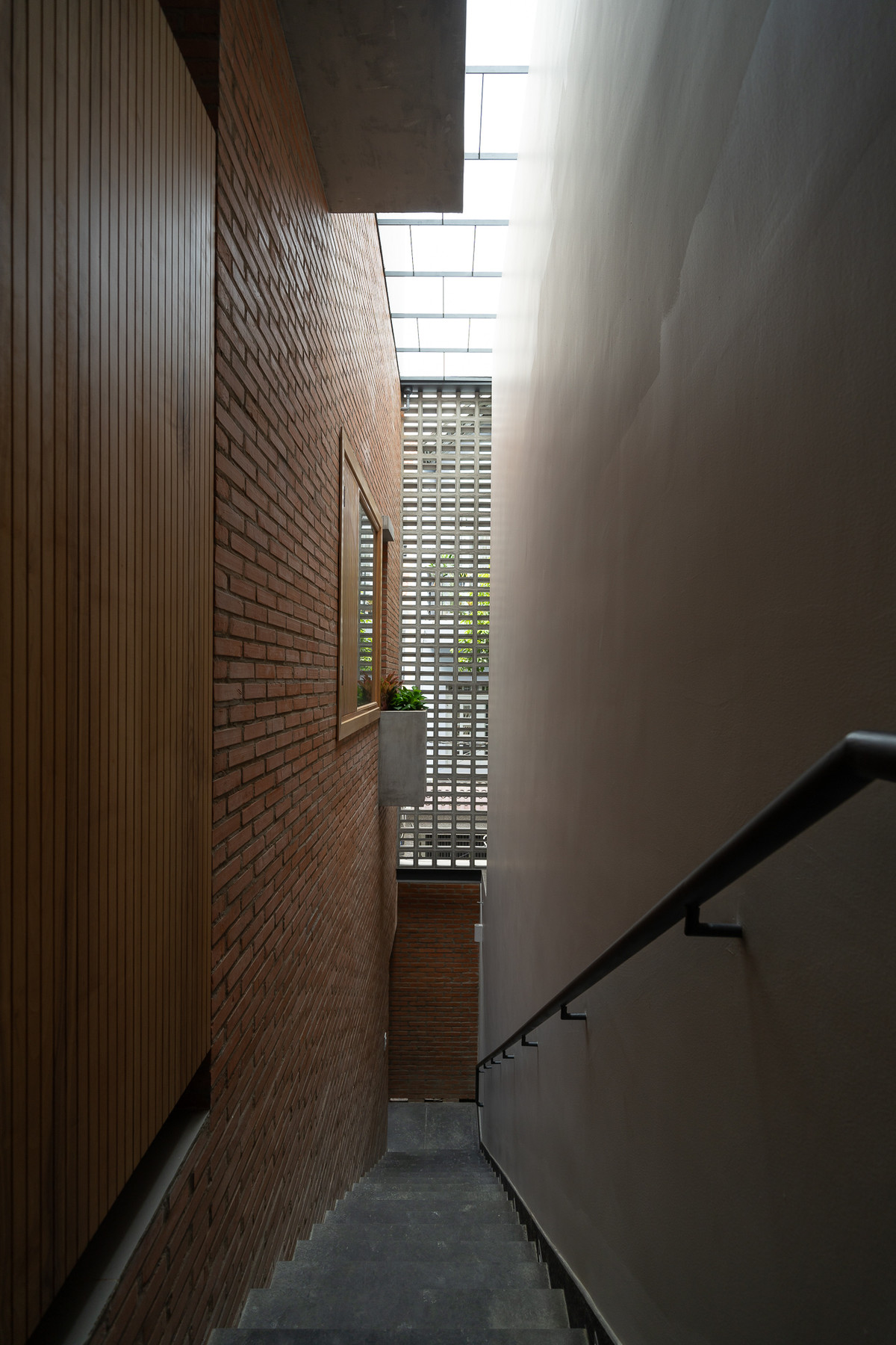 Mảng tường này dẫn dắt cầu thang từ trệt lên lầu như một cầu thang ngoài trời và tạo ra ranh giới giữa ngôi nhà với khoảng hẻm nhỏ bên hông nhà. Ảnh: Quang Dam/G+architects