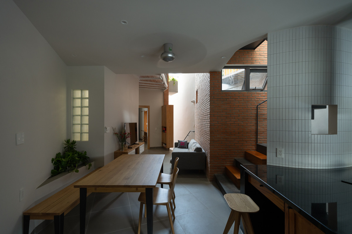 Mảng tường thứ 2 xoay 1 góc 15 độ tạo ra khoảng thông tầng cho lầu 1 và mở giếng trời cho tầng trệt (khoảng sân nơi có phòng trọ), cũng như dẫn lối cho cầu thang lên lầu 2. Ảnh: Quang Dam/G+architects