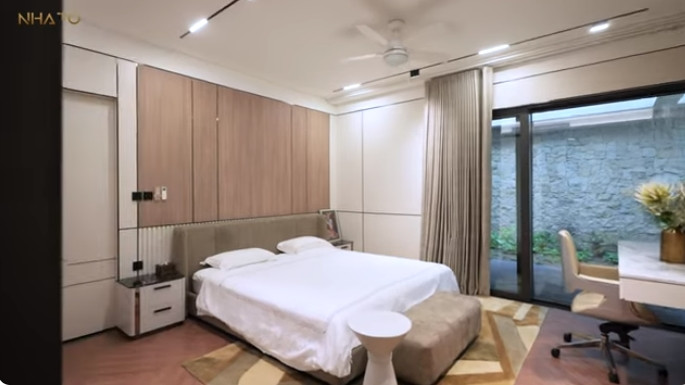 Một phòng ngủ phụ có cửa kính lớn nhìn thẳng ra sân vườn.