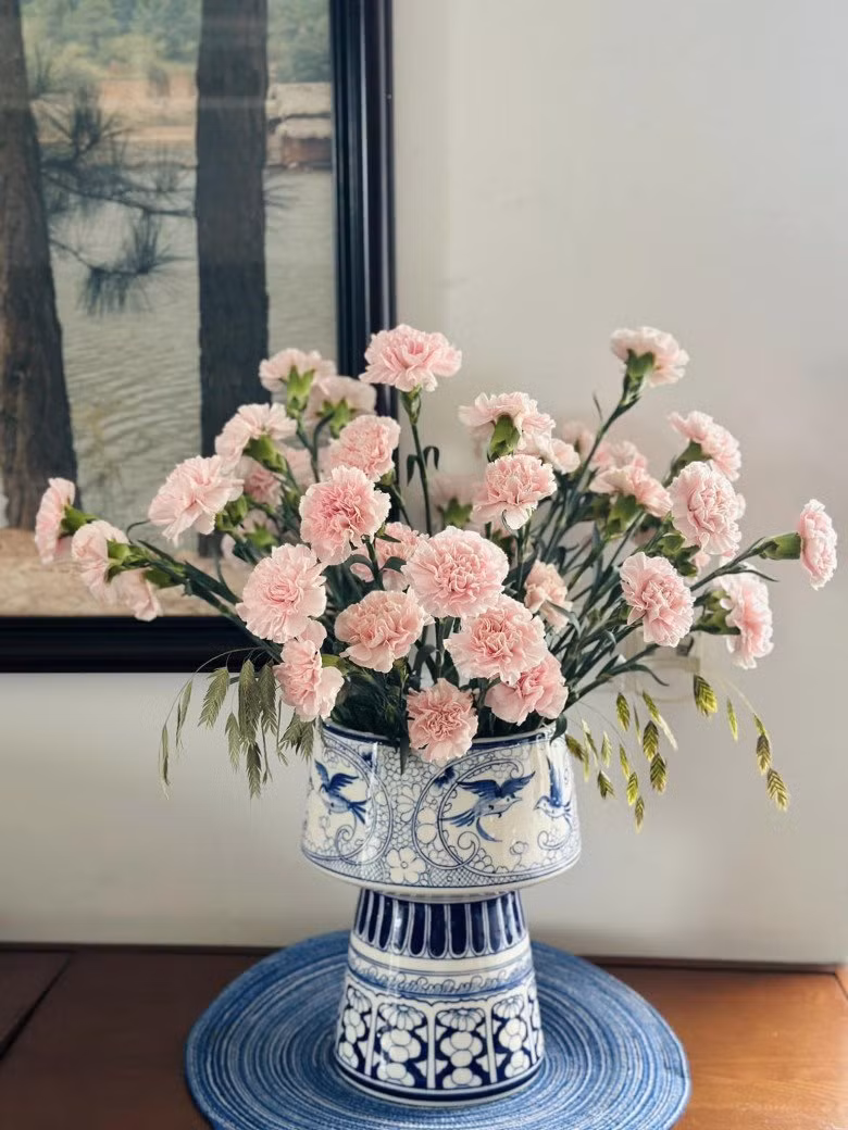 Bình hoa độc đáo cắm trên chai thủy tinh nằm ngang và được cố định bằng dây xích.