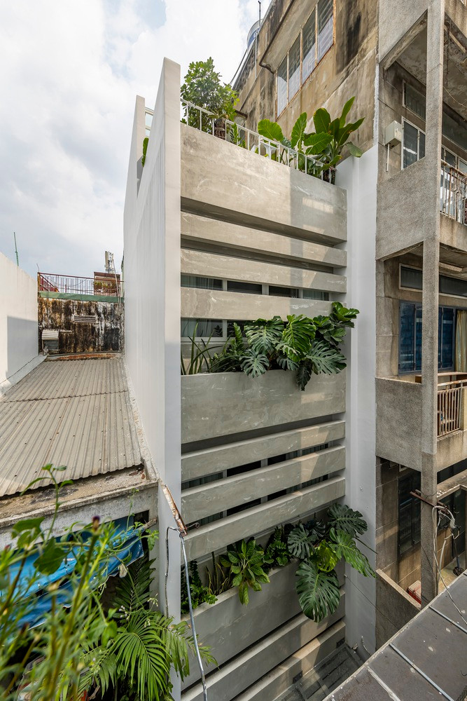 Ngoài mặt tiền, các ô cửa sổ bê tông nằm ngang kết hợp mảng xanh xen kẽ giống như một tấm màn lớn tự nhiên che chắn cho không gian bên trong khỏi những tác động từ bên ngoài.