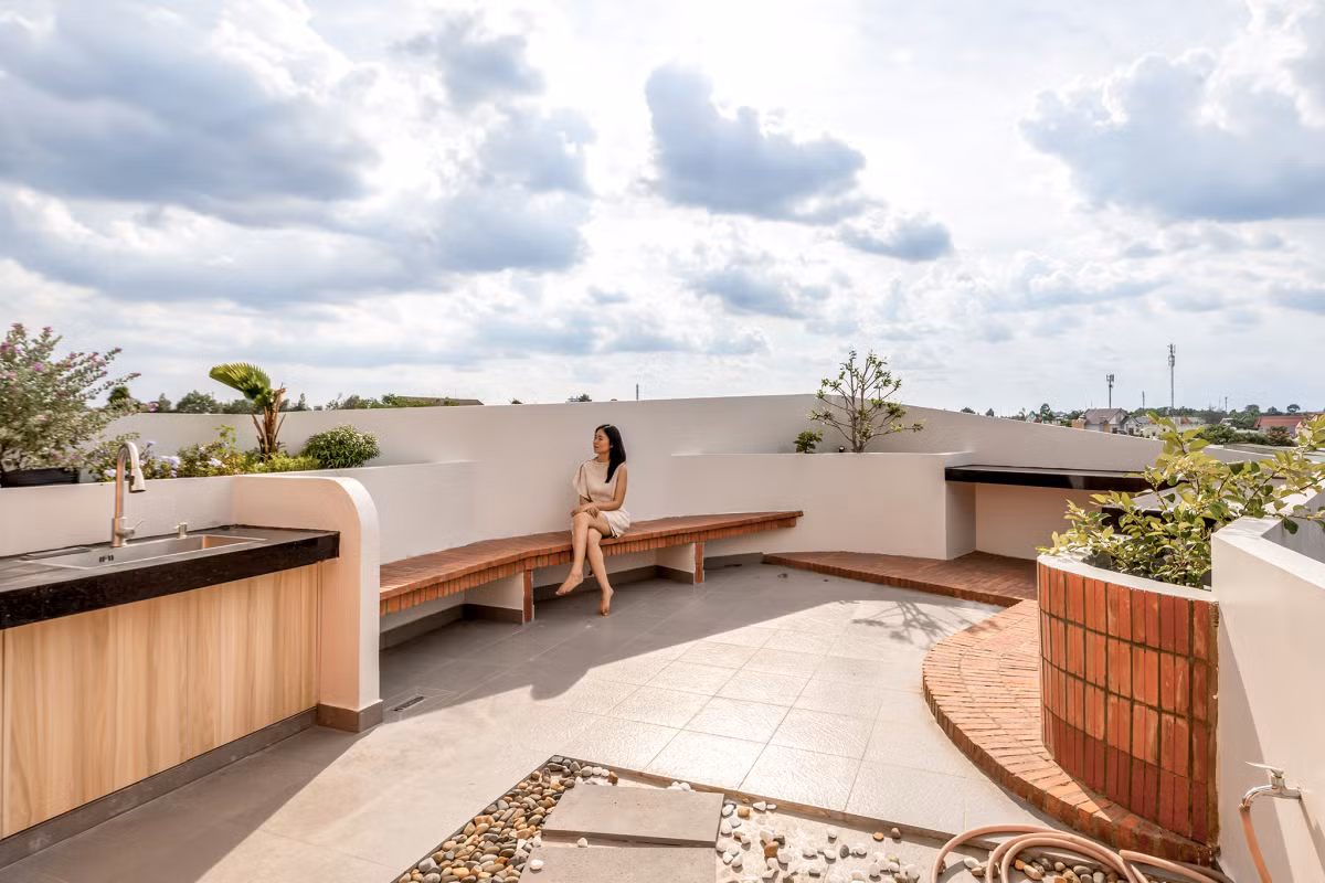 Khu vực mái được sử dụng như một sân thượng lớn. Phần phía trước đóng vai trò là không gian thư giãn cho gia đình và bạn bè. Phía sau được sử dụng làm khu vực phơi đồ, kết hợp với việc trồng cây ăn quả theo sở thích của chủ nhà. Ảnh: Minq Bui