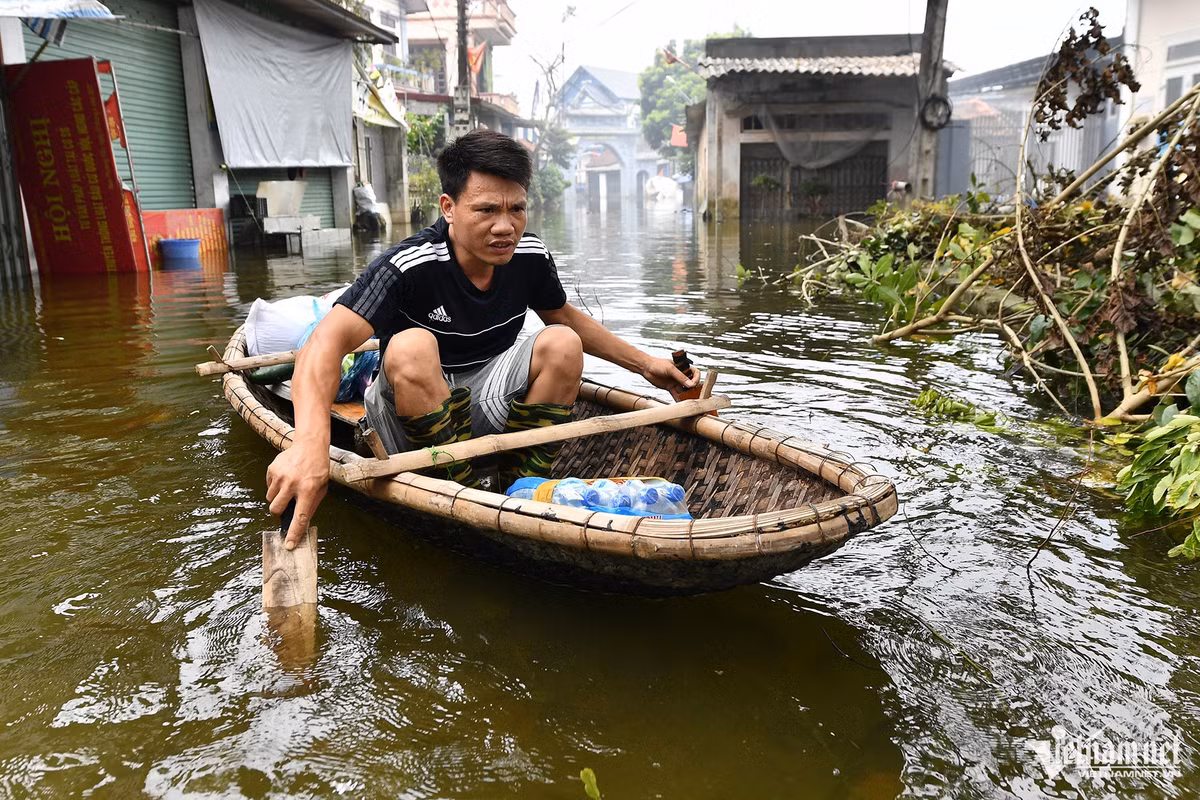 Một người đàn ông vừa được phát nước uống, anh đưa hàng lên thuyền rồi tự chèo về nhà.