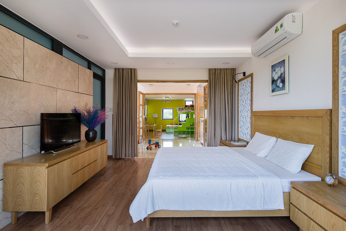 Trên tầng 2, phòng ngủ của bố mẹ và hai con được bố trí đối diện nhau và kết nối qua một khoảng đệm.