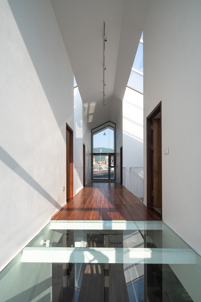 Hành lang có tầm nhìn hướng về phía đồi núi và sàn kính giúp mang ánh sáng xuống các tầng dưới. Ảnh: Triệu Chiến