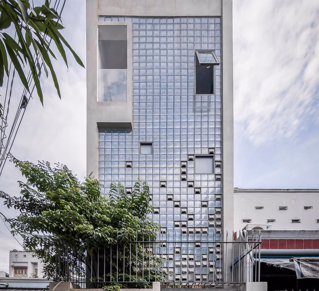 Thay vì đổ tường như những ngôi nhà thông thường khác, kiến trúc sư sử dụng toàn bộ kính cho mặt tiền, điểm xuyết thêm gạch bông gió, giúp nhà một trệt hai lầu như khoác lên mình chiếc áo lấp lánh. Ảnh: Minq Bui