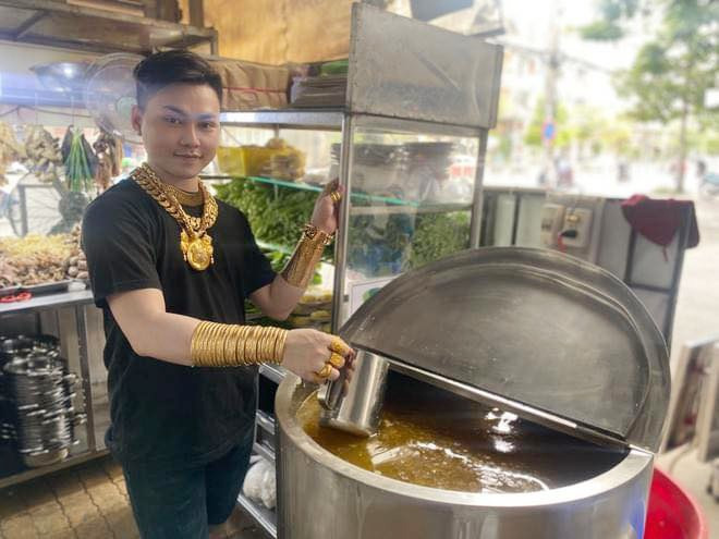 Gần đây, mạng xã hội rầm rộ chia sẻ loạt ảnh chàng trai đeo vàng “kín người” đứng bán lẩu bò bình dân ở TP HCM. Đó là chàng thanh niên Nguyễn Cường (22 tuổi). Ảnh: Facebook