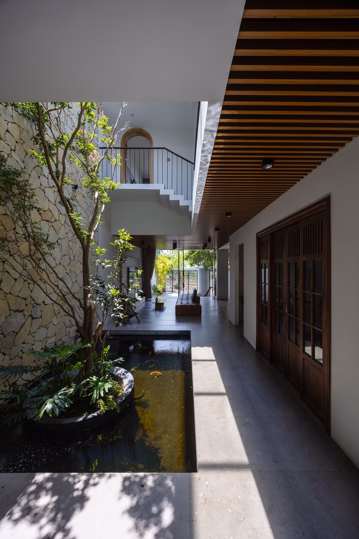 Mảng đá tự nhiên xuyên suốt giếng trời là điểm nhấn chính về không gian, khi kết hợp với các vật liệu khác như bê tông, gạch mộc, gỗ và cây xanh sẽ tạo nên cảm giác mộc mạc, gần gũi với tự nhiên. Ảnh: Triệu Chiến