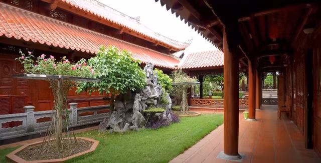 Phía sau nhà chính là dãy nhà ngang dùng làm phòng ăn và nhà bếp, nối với nhau bằng hành lang lát gạch đỏ sạch sẽ. Ảnh chụp màn hình NhaTo