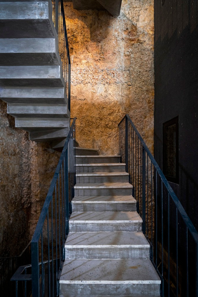 Công trình có một phần khoét sâu vào ngọn đồi; bằng phương pháp thi công đặc biệt, kiến trúc sư đã vô tình tạo nên một bức tường đất tự nhiên đầy hấp dẫn. Sự vô tình này được giữ lại nhằm gia tăng kết nối với các yếu tố địa phương cả về vật chất và tinh thần.