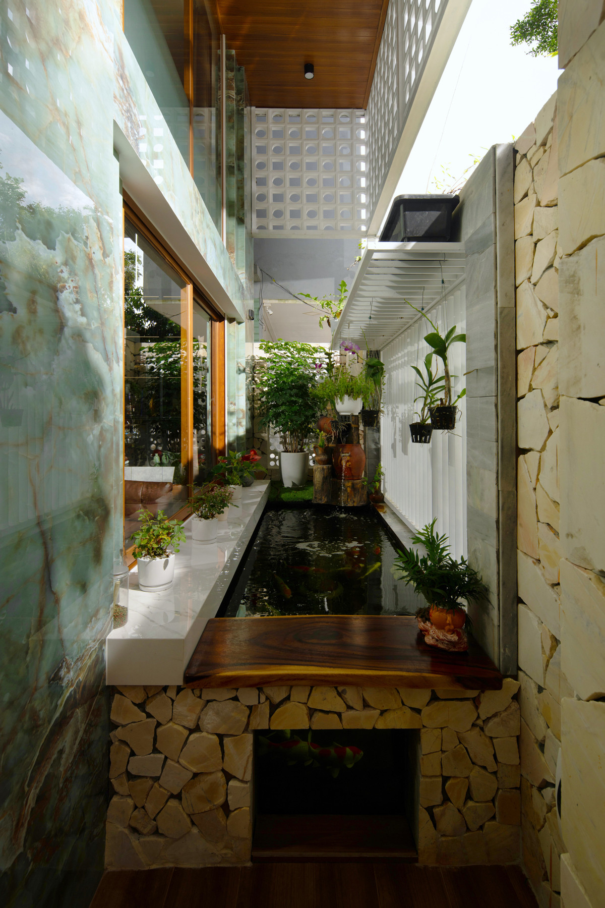 Để giải quyết vấn đề trên, kiến trúc sư lựa chọn giải pháp hồ cá làm lớp đối lưu không khí cũng là vùng không gian đệm có chức năng phân cách không gian sống bên trong với môi trường bên ngoài.