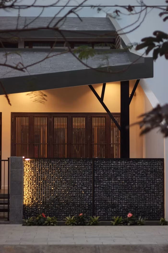 Phần mái “vén” có chức năng đón gió vào nhà được chống đỡ bằng một cây cột ốp gỗ.