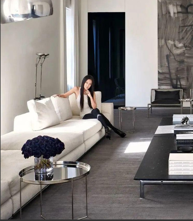 Tường trắng trang nhã kết hợp sàn gỗ và nội thất cao cấp, bao gồm ghế sofa da màu đen, bàn kính, thảm trải sàn màu trung tính tạo nên sự tương phản bắt mắt.