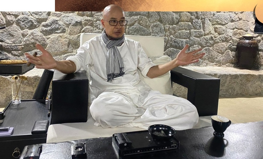 Ông Đặng Lê Nguyên Vũ ngồi khoanh chân trên chiếc ghế viền gỗ đen, nệm trắng. Ảnh: Dân Việt