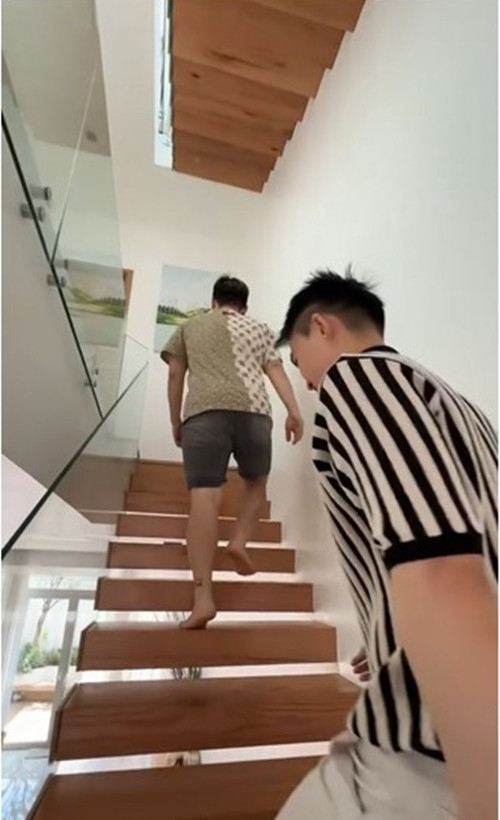 Cầu thang gỗ bậc hở với lan can kính trong suốt mang đến sự thoáng đãng cho căn nhà.