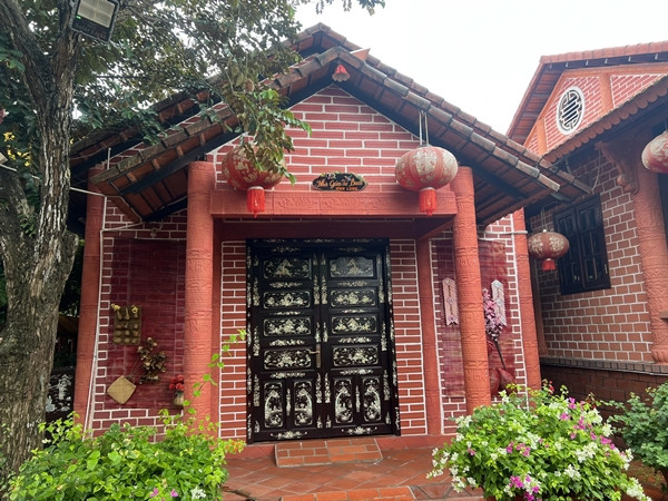 Ngôi nhà được xây dựng theo kiến trúc 3 gian, 2 chái truyền thống Nam Bộ. Phía cổng bên ngoài và tường rào trang trí bằng bích họa gốm đỏ. Ảnh: Người lao động
