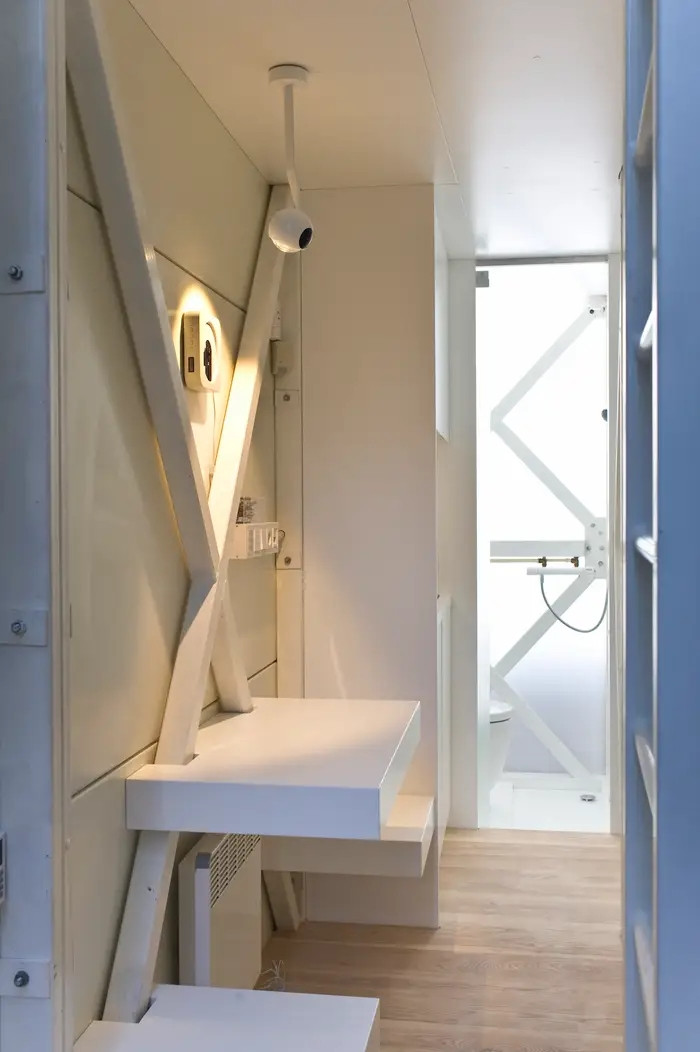 Phía sau khu vực tiếp khách là căn bếp nhỏ với bồn rửa, bếp nấu và tủ lạnh mini, xa hơn là phòng tắm nhỏ có vòi sen.