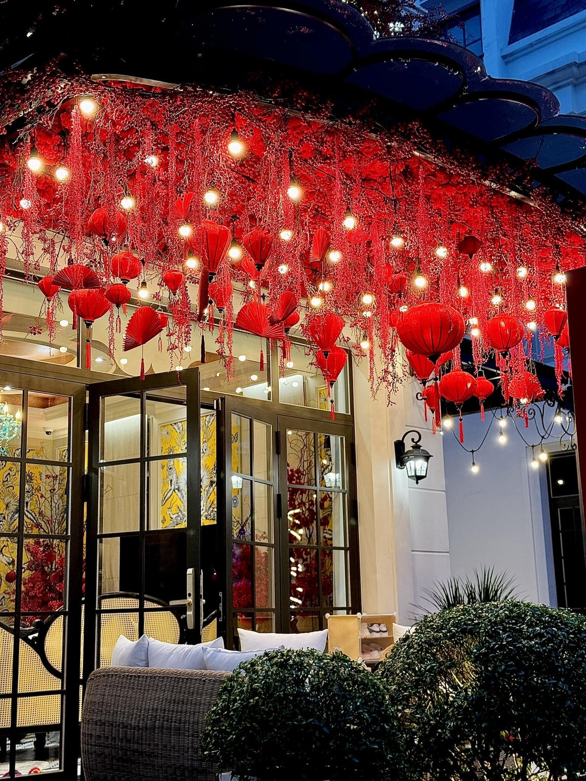 Mái hiên trước cửa nhà treo đèn lồng và rất nhiều đông đào màu đỏ rực.